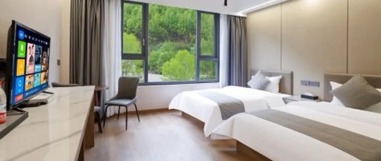 Chambre standard à deux lits de l'auberge du village de Siguniang, avec de grandes fenêtres sur la colline boisée.