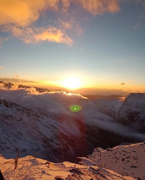 Lever de soleil au-dessus d'une mer de nuages, vu depuis la crête au-dessus du camp de base du Siguniang, avec les premières lueurs sur la neige.